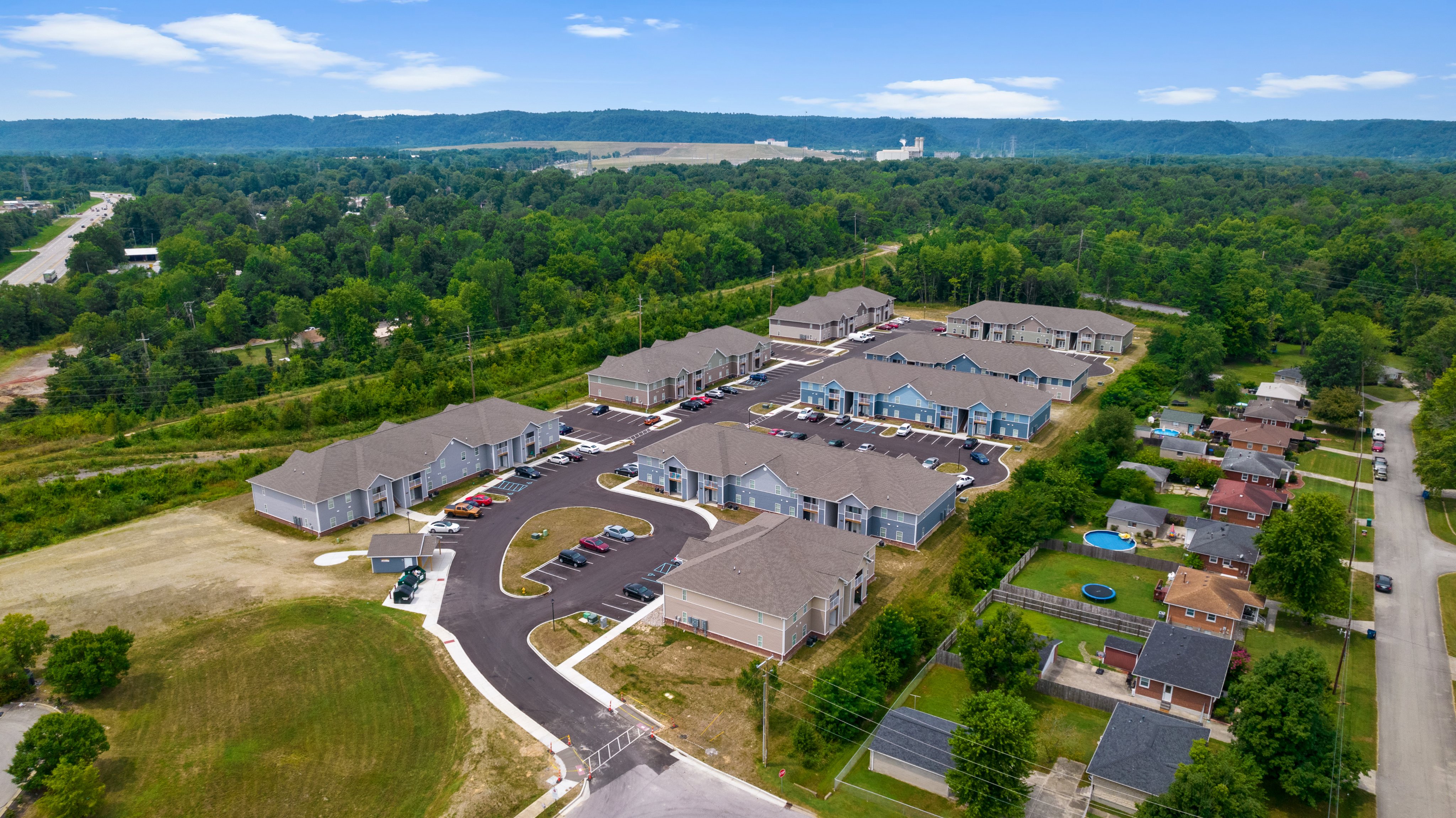 Aerial drone view of Cane Run Station apartment community in Louisville, Kentucky, showing blue and gray buildings, parking courts, and surrounding trees